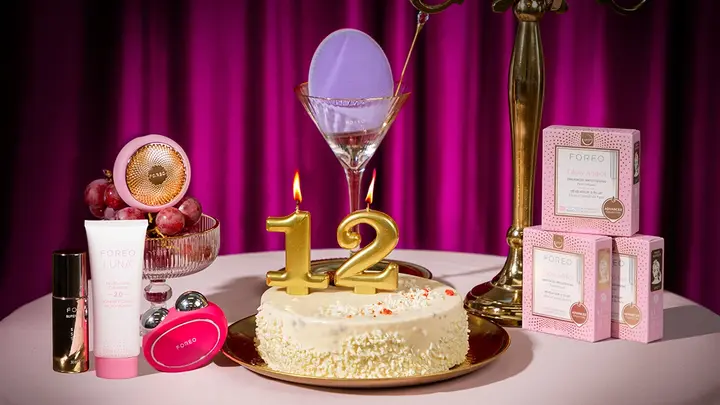 FOREO devices and cosmetics around a birthday cake with the candles showing the number 12